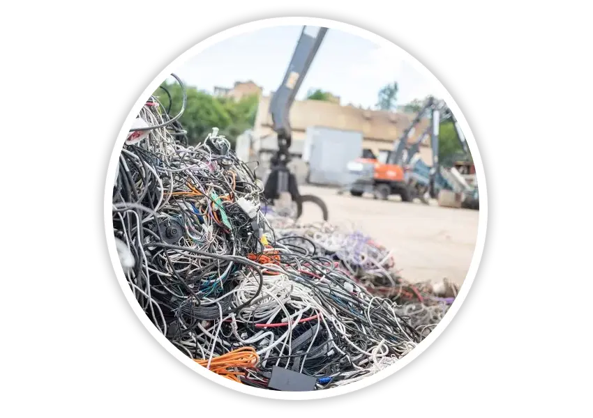 Large pile of recycled cables at outdoor recycling yard with cranes preparing materials for eco-friendly road safety product manufacturing