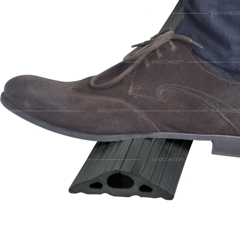 Foot pressing down on the 1-channel floor cable cover, demonstrating its durability under pressure