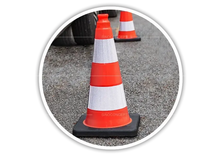 Orange traffic cone with black weighted base and reflective collar placed on asphalt road for traffic safety and vehicle guidance