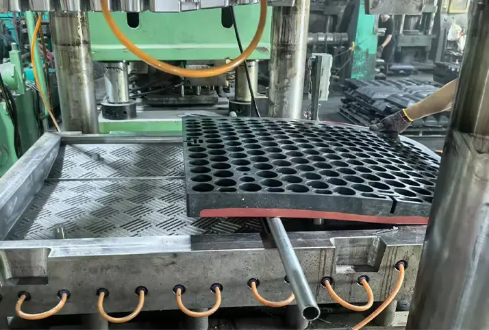 Close-up of a molding machine producing a speed cushion, with the product being ejected from the mold in a manufacturing facility