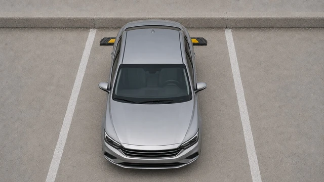 Top view of a silver car correctly positioned against a black plastic-rubber composite wheel stop in a marked parking space.
