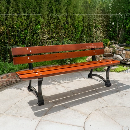 Outdoor benches and seating with wooden slats and cast iron legs installed in a landscaped public area