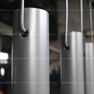 Steel street bollards suspended on a finishing line during factory production