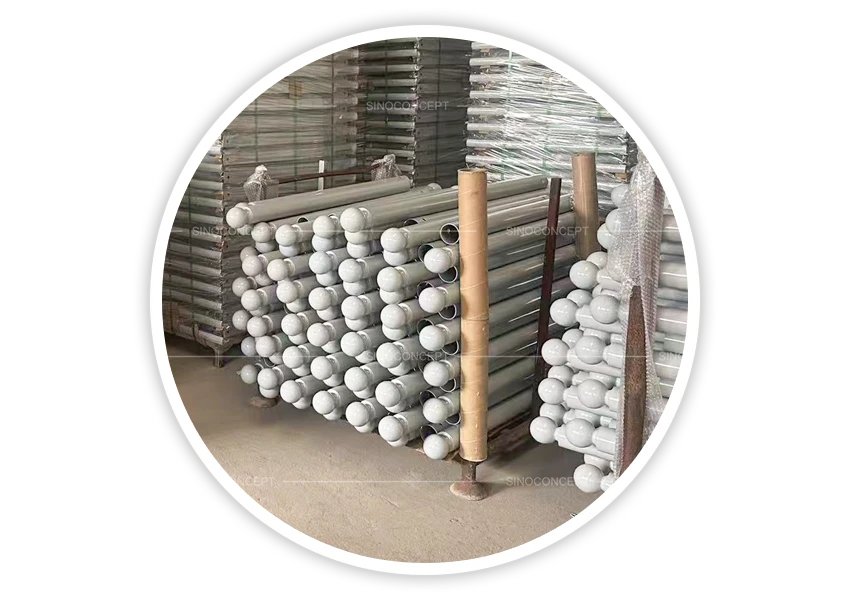 Grey steel street bollards with white ball tops stacked in warehouse for storage and shipment