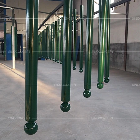 Green street bollards with zinc-rich powder coating hanging during factory surface treatment
