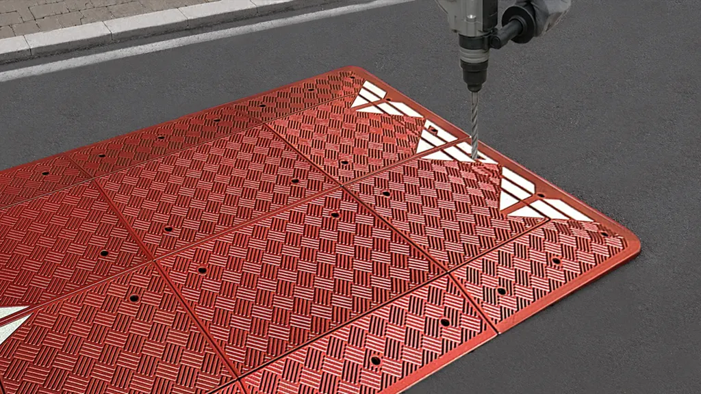 Marking fixing hole positions on assembled speed cushion sections before drilling and anchoring.
