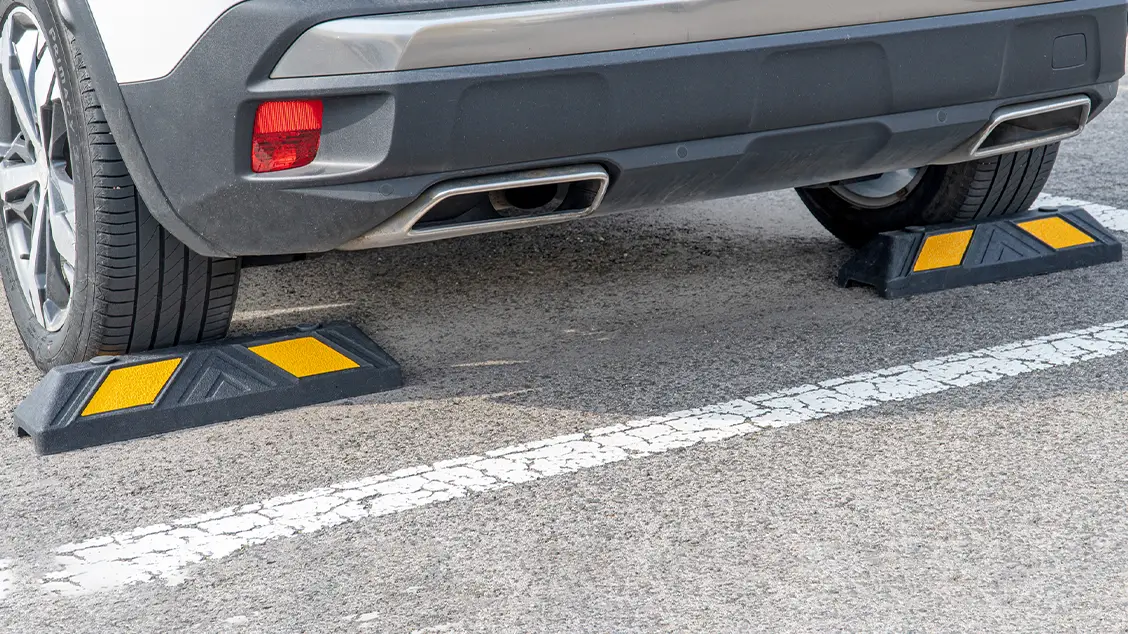 Rubber wheel stops installed in a parking space to control vehicle positioning