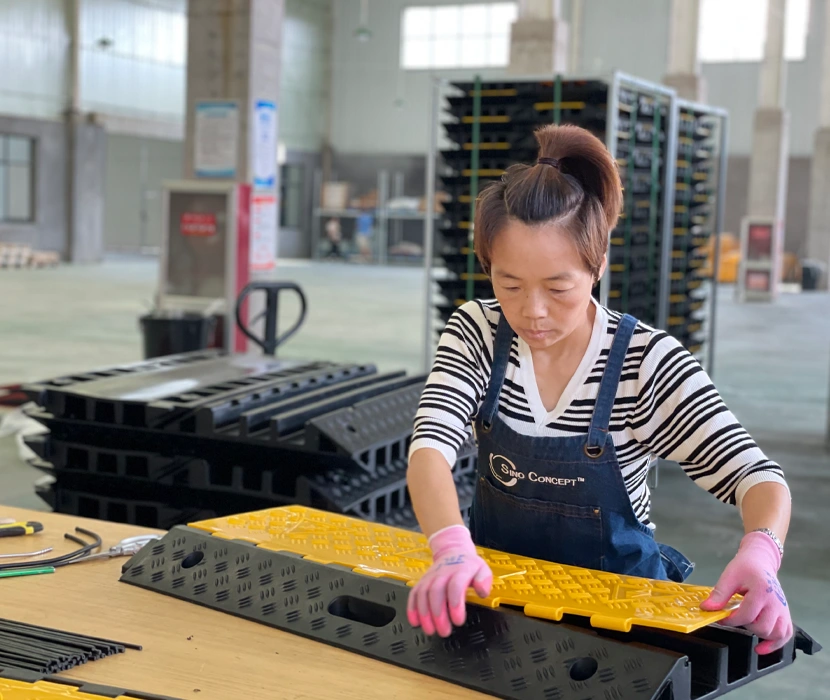 Sino Concept worker assembling a black and yellow heavy-duty cable ramp at a production site in China
